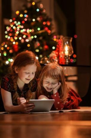 sorelle utilizzando tablet pc sul pavimento durante il periodo natalizio