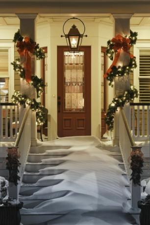 invitante porta di Natale con la neve sulle scale del portico e sulla ringhiera